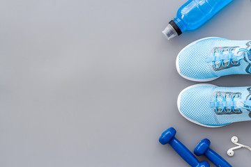 Sport background with sneakers and dumbbells on grey table top view copy space