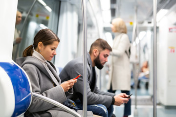 Fototapeta na wymiar Young woman with phone in subway car