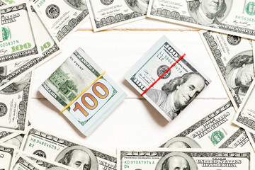 Frame of one hundred dollar bills with stack of money in the middle. Top view of business concept on white wooden background with copy space