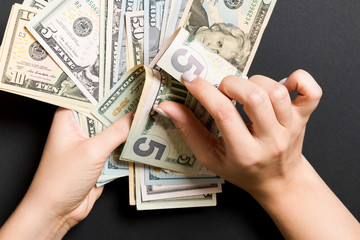 Businesswoman's hands counting five and other dollar bills on colorful background. Salary and wage concept. Top view of Investment concept