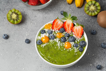 Healthy Breakfast green smoothie bowl with banana, kiwi, strawberry, blueberry and spinach.