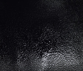 Water Drops on black leather in bright light