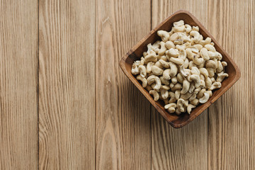 cashew nuts in a bowl on a wooden background. Rustic style. Vegetarian food.