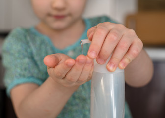Kid girl is spraying sanitaizer or alcohol gel on her hands. Antiseptic cleaning gel in child's hands. Close up. Hygiene during coronavirus epidemic.