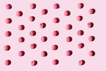 Bunch of vibrant colored quail eggs placed on side of pink background during Easter celebration