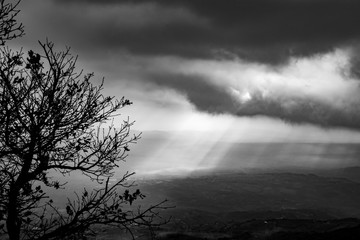 Fototapeta premium black and white image of sunbeams in the clouds illuminate the Telesina Valley, Benevento, Campania, Italy
