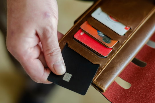 Hand takes out a bank card from the wallet.