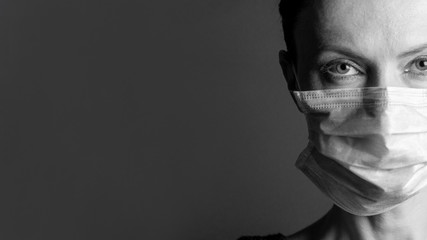 Girl wears protective mask. Coronavirus. Close up portrait of young woman wearing medical mask, black and white