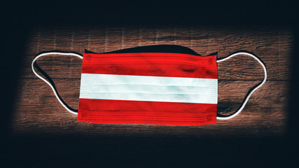 Austria National Flag at medical, surgical, protection mask on black wooden background. Coronavirus...