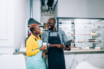 Black barista showing tablet to colleague