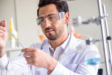 Attractive happiness scientist man lab technician assistant analyzing sample in test tube at laboratory. Medical, pharmaceutical and scientific research and development concept.