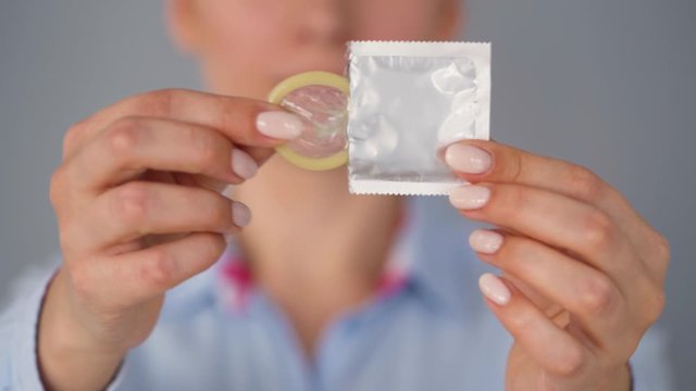 Female hands demonstrating condom before camera, safe sex, contraception