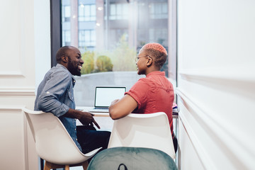 Obraz premium Black happy freelancer talking to coworker in office