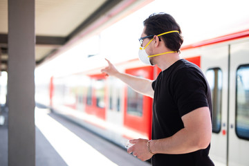 Mann in Corona-Zeiten am Bahnhof, er trägt eine Atemmaske und Gummihandschuhe - obrazy, fototapety, plakaty