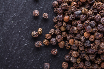 aromatic black pepper on a dark stone background