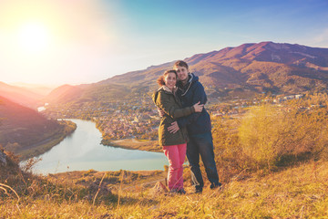 Hugging couple in love stands on the hill with beautiful evening view of mountains valley with Mtskheta city, Kura and Aragvi rivers. Georgia country © vvvita