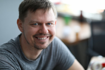Close-up of smiling middle-aged man looking in camera. Cheerful attractive person dressed in grey shirt. Copy space in right side. Modeling and happiness concept