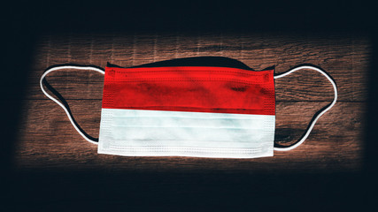 Indonesia National Flag at medical, surgical, protection mask on black wooden background....