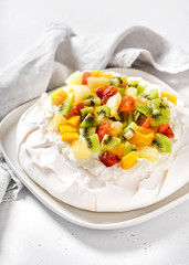 Delicious pavlova meringue cake with kiwi, mango, pineapple, blood orange slices and whipped cream. Selective focus.