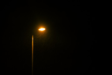 Fototapeta na wymiar A glowing street lamp at rainy night.