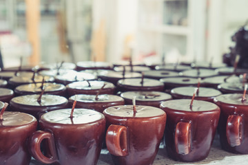 Coffee cup candles arranged in shelves and sorted by color in a candle shop.