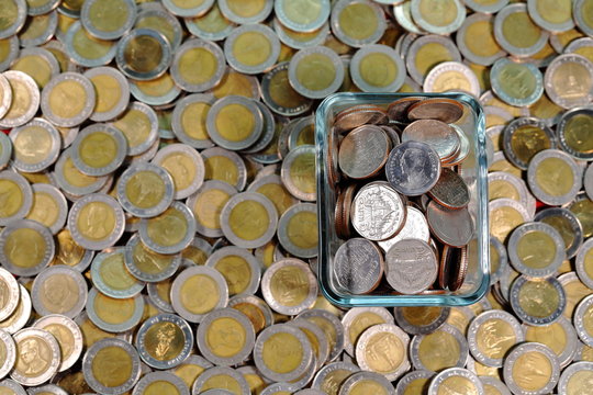Thailand five baht coin in a cup Placed on a pile of ten baht coins View from above