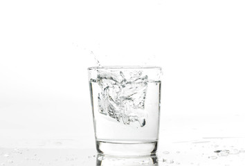 Glass with water and ice on a white background. Glass of mineral water and ice on white background.