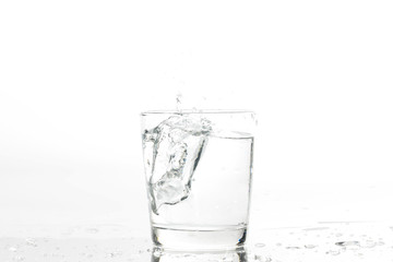 Glass with water and ice on a white background. Glass of mineral water and ice on white background.