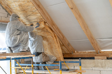 Professional worker in overalls working with rockwool insulation material - obrazy, fototapety, plakaty