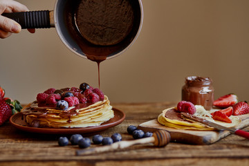 Homemade crepes, tasty thin pancakes with chocolate and fruits on the rustic table