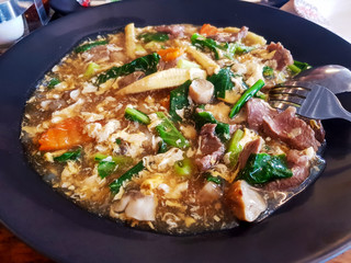 Fried noodle with beef and vegetable in a black plate at the restaurant