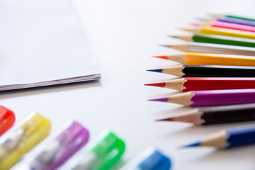 Colorful pens, color pencils and white paper for note or drawing on white table. 