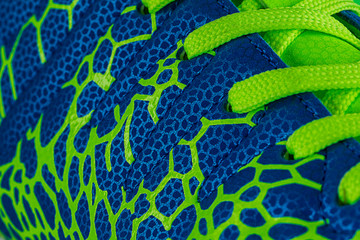 Fragment of a blue sneaker with green laces close up. Sneaker texture