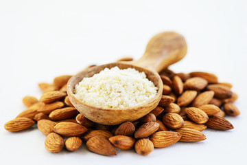 Almond flour in a wooden spoon on a pile of almonds. Gluten free food.