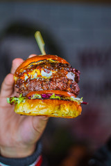 Mano cogiendo una hamburguesa de queso de cabra 