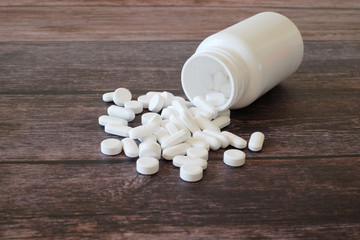 Fototapeta na wymiar Medical tablets spilling out from plastic pill bottle on wooden background. Paracetamol 500 mg. Medicine and healthcare concept. 