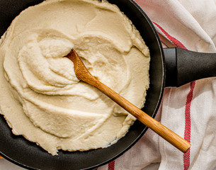 Cauliflower bechamel sauce on a pan on top of a wooden board. Flat lay. Top view. 