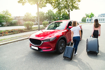 Young women going to travel by car with luggage