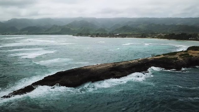 Stormy waves crashing against Laie Point, O'ahu, Hawaii, aerial arc panoramic