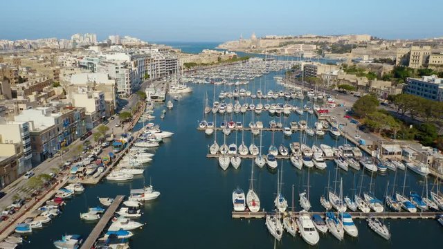 Aerial view of Msida marina, yachts, boats. Sunny day, Valletta city on background. Camera moves forward. Malta country