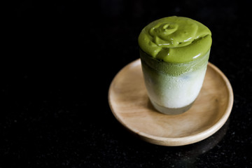 Iced Dalgona Matcha Latte, a creamy whipped matcha on fresh milk, on black background