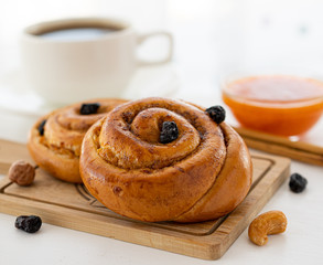 Bun with raisins and cinnamon on a wooden board