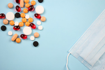 pills of different colors on a blue background and protective mask