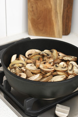 Chopped champignon mushrooms frying in pan