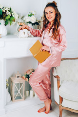 Young adut woman in pink silk robe holding a pet rabbit