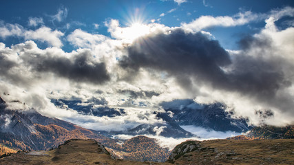 Amazing view of the valley in autumn season in Dolomites with sun shining through the clouds