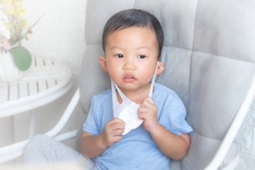 Boy teen takes off medical mask on blue background. child with flu, influenza or cold protected from viruses, pollution in bad epidemic situation, among patients with coronavirus.