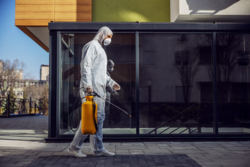Cleaning and Disinfection outside around buildings, the coronavirus epidemic. Professional teams for disinfection efforts. Infection prevention and control of epidemic. Protective suit and mask
