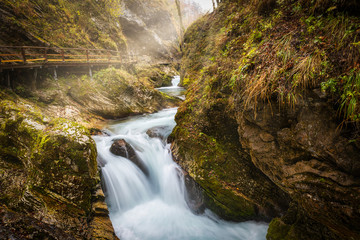 Beautiful waterfall and wooden pathway in Vintgar gorge with morning sunlight, famous touristic...