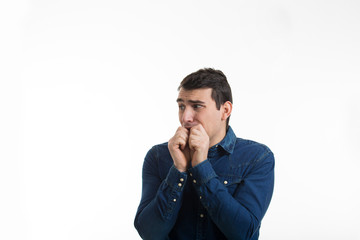 Scared and worried young man biting finger nails being afraid isolated on white background.